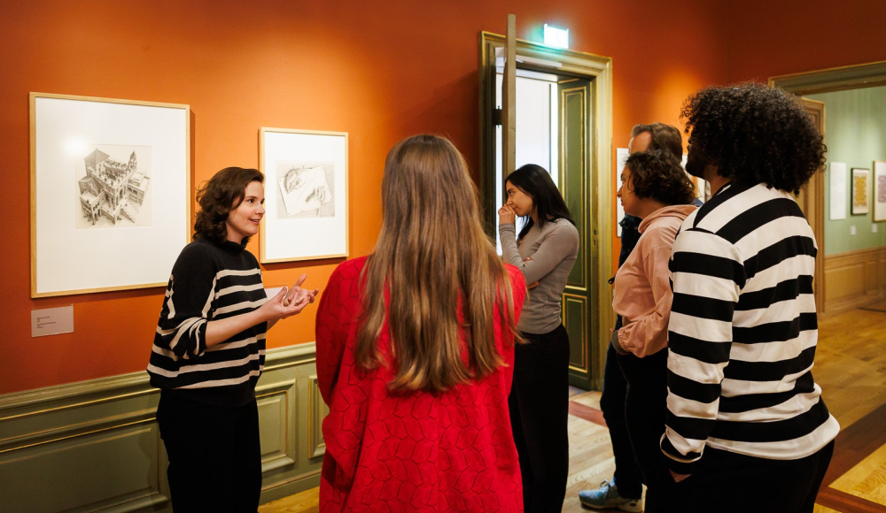 Groep mensen voor twee kunstwerken tijdens een rondleiding in een museum Groep mensen voor twee kunstwerken tijdens een rondleiding in een museum